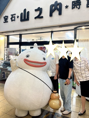 山之内時計眼鏡店の店頭に立つシマバランと笑顔の人々